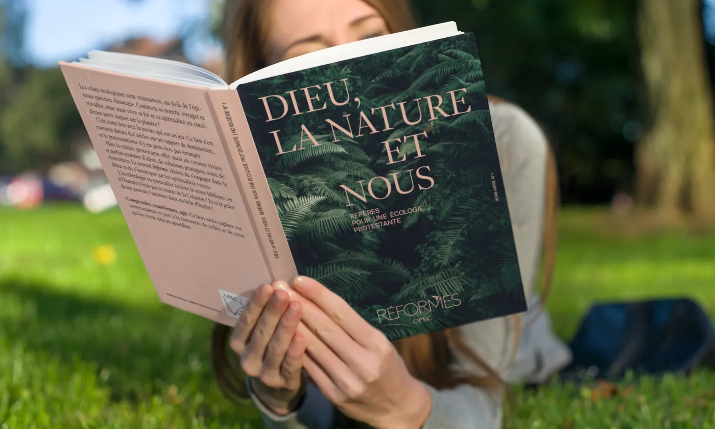 Le mook « Dieu, la nature et nous, Repères pour une écologie protestante» lu dans un pré.  Photomontage (Eh oui, notre mook est en cours de fabrication)
